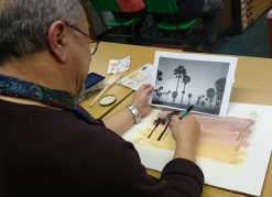 Man drawing palm tree silhouettes against a sunset