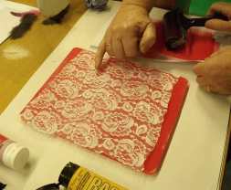 hand pointing at lace on coloured paint