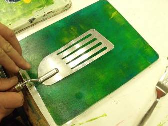 hands imprinting a fish slice into paint